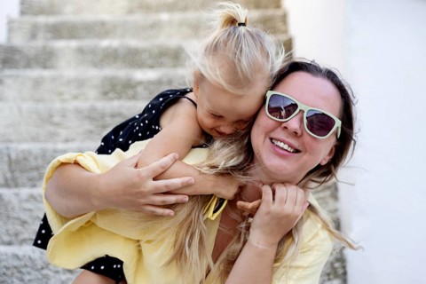 A joyful mother and daughter share a playful moment outdoors, epitomizing the bond of family. The