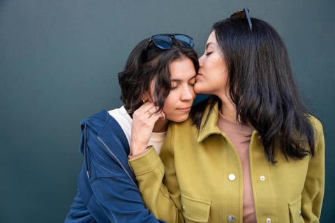 A tender moment between a couple as one partner gently kisses the other's forehead, showing