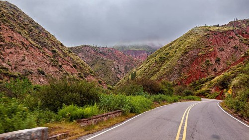 Empty road winds through a mountainous landscape rich in vegetation, roads through the landscape of
