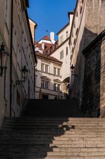 A narrow medieval street with steep stone stairs, surrounded by historic buildings with ornate