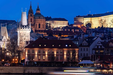 A beautiful evening shot of Prague featuring illuminated historical architecture and vibrant light