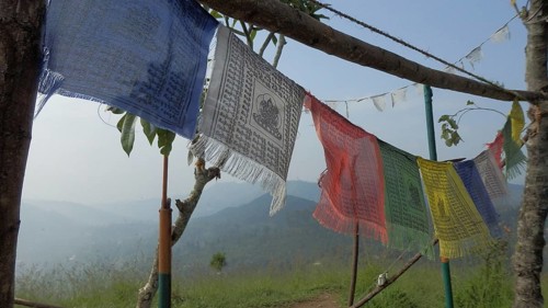 Colourful Buddhist prayer flags waving in the wind with a view of a mountainous landscape in the