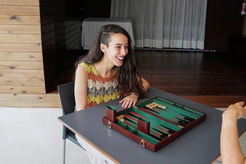 A woman with long hair smiles as she engages in a friendly game of backgammon indoors The