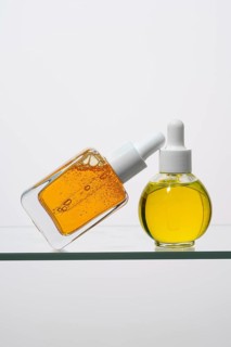 Two elegant pipette bottles filled with vitamin C serum are showcased on a glass surface