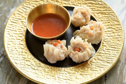 A close-up image of freshly steamed Asian dumplings filled with finely chopped vegetables and