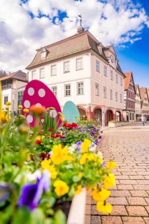 Colourful flowers and Easter decoration in front of half-timbered houses on a sunny day, Nagold,