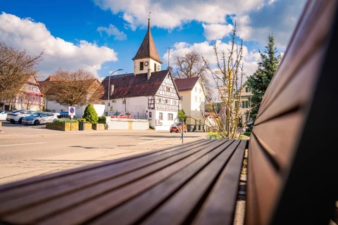 Half-timbered church and half-timbered houses in the city center, with a park bench in the