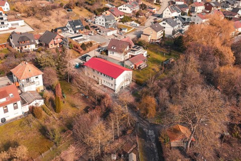 House with a distinctive red roof in a residential area surrounded by gardens and trees, Ötisheim,