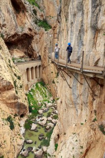 Two hikers on a narrow bridge over a gorge on the Caminito del Rey, Malaga, Spain
