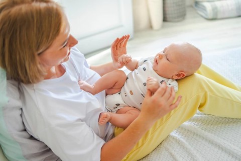 A mother joyfully interacts with her baby, creating a warm and nurturing environment. The cozy and