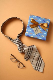 Top view of a stylish Father's Day gift presentation featuring a patterned tie, elegant glasses,