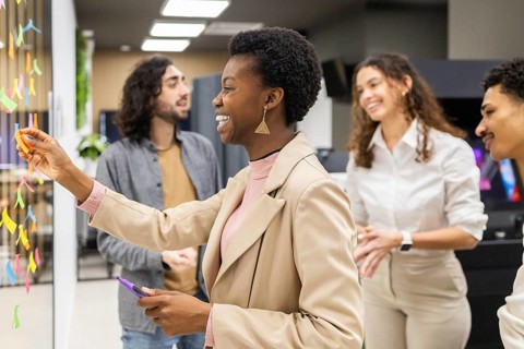 A diverse group of colleagues engaged in a brainstorming session in a modern office. Smiling and
