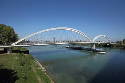 Modern tram bridge Pont Beatus-Rhenanus across the Rhine with cargo ship, arched bridge, Kehl,