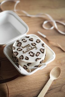 Charming mini birthday cake with a trendy leopard print theme enclosed in a white takeout box,