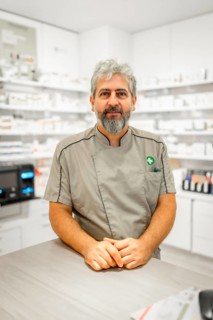 Vertical portrait of a mature pharmacist with uniform standing in the store