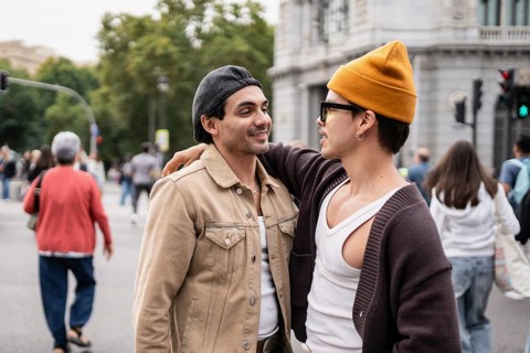 A loving gay couple walking arm-in-arm on a bustling city street. The two individuals are relaxed,