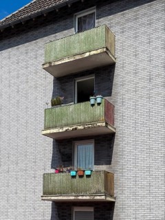 Balconies with privacy screens and colourful flower boxes on a house with grey clinker brick in