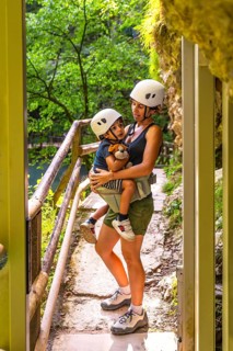 Mother carrying her son while wearing safety helmets during a visit to the scenic vintgar gorge,