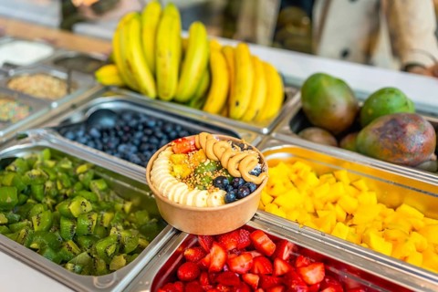 Acai smoothie bowl topped with bananas, blueberries, strawberries, kiwi, mango, nuts, and peanut