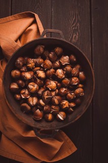 Roasted chestnuts, in an iron pan, wooden table, top view, no people, rustic style