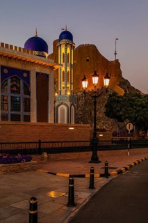 The illuminated Al Khor Mosque with three-light candelabra, behind the Milani Fort, Muscat, Arabian
