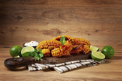 Corn ribs, with cream sauce, spices and lime, appetizer, on a wooden cutting board, homemade, no