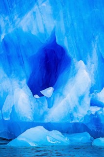 Cave into a glacier by the sea with turquoise colored ice, Svalbard, Norway