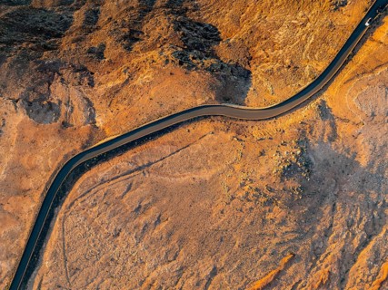 Road on cliffs through dry landscape in evening light, top-down shot, near Mirador del Porrito,