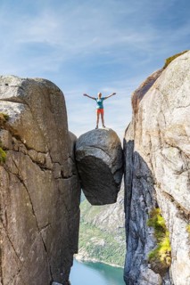 Woman standing onKjeragbolten, jammed rock above the Lysefjord, Kjerag, Lysebotn, Rogaland, Norway