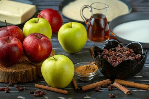 Various baking ingredients such as apples, cinnamon, sugar, rum and raisins