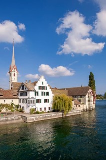 Half-timbered house and church tower on a clear river under a blue sky, view of the old town of