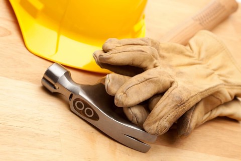 Yellow Hard Hat, Gloves and Hammer on Wood Surface