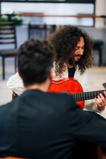 From above male friends playing guitars at table in music studio