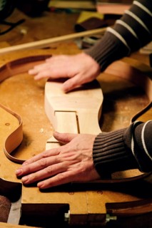 A luthier skillfully shapes components in a bass guitar workshop, demonstrating precision and
