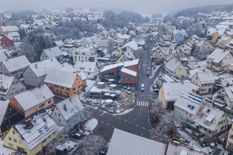 Panoramic view of a snowy village with many houses and roads in a foggy winter landscape, Gechingen