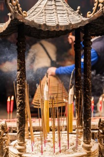 Back view of unrecognizable person participating in a traditional incense burning ceremony at a