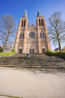 Large brick church with double towers and stairs under blue sky, Sacred Heart of Jesus, Bregenz,