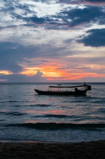 A traditional boat is silhouetted against a stunning sunset over the tranquil waters of Koh Rong
