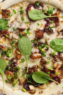 Close up view of a freshly baked gourmet pizza topped with chanterelles, truffle sauce, mozzarella,