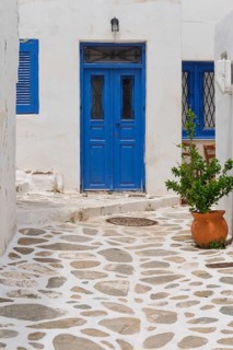 Idyllic Mediterranean scene with blue door, white walls and clay pot on cobbled alley, alley in the