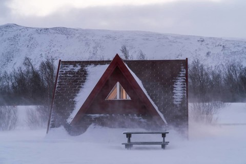 Cozy A-frame cabin nestled amidst the snowy wilderness of Swedish Lapland. The serene winter