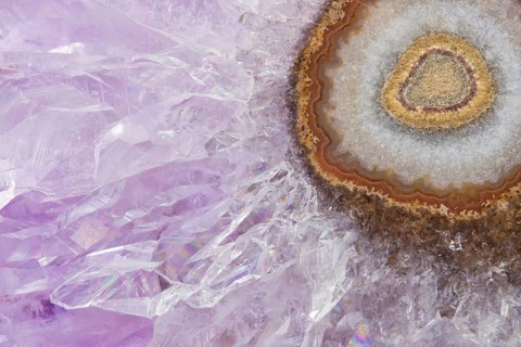 Detailed macro image of an amethyst stalactite slice, featuring sparkling purple crystals radiating