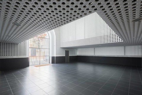 Minimalist auditorium interior featuring geometric patterns on the walls and ceiling. Large window