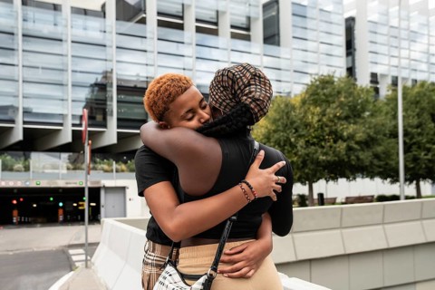 An LGBT multiethnic couple shares an affectionate embrace in an urban setting, showcasing love and