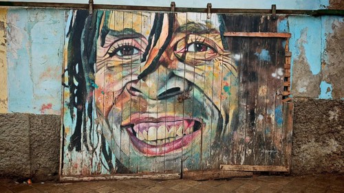 Large portrait of a smiling face on wooden gate, mural, graffiti, in colorful abstract version,