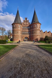 City gate, historic brick building, footpath made of sand, garden with lawn, Holstentorplatz,