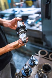 Vertical close-up of an unrecognizable caucasian male technician holding a piece of milling machine