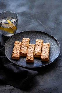 Crispy puff pastry sticks filled with sweet apricot jam, elegantly arranged on a sleek black plate.
