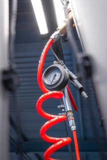 Close-up of a pressure gauge in a workshop with a bright red spiral cable, Waldbike Manufaktur,