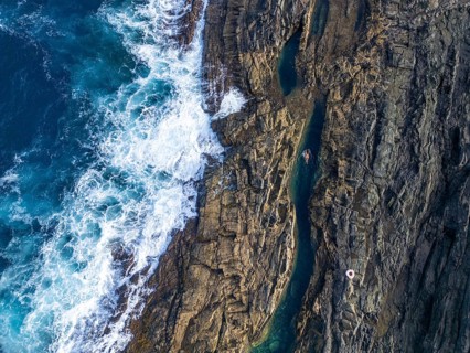 Top view of natural rock pools in Tindaya, Fuerteventura, featuring a woman leisurely swimming in